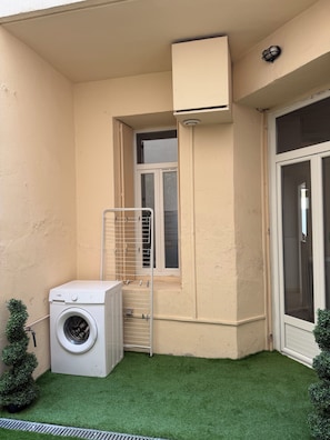 A laundry area with a washing machine, a drying rack, and a small window. - Vrbo Property (Béziers)