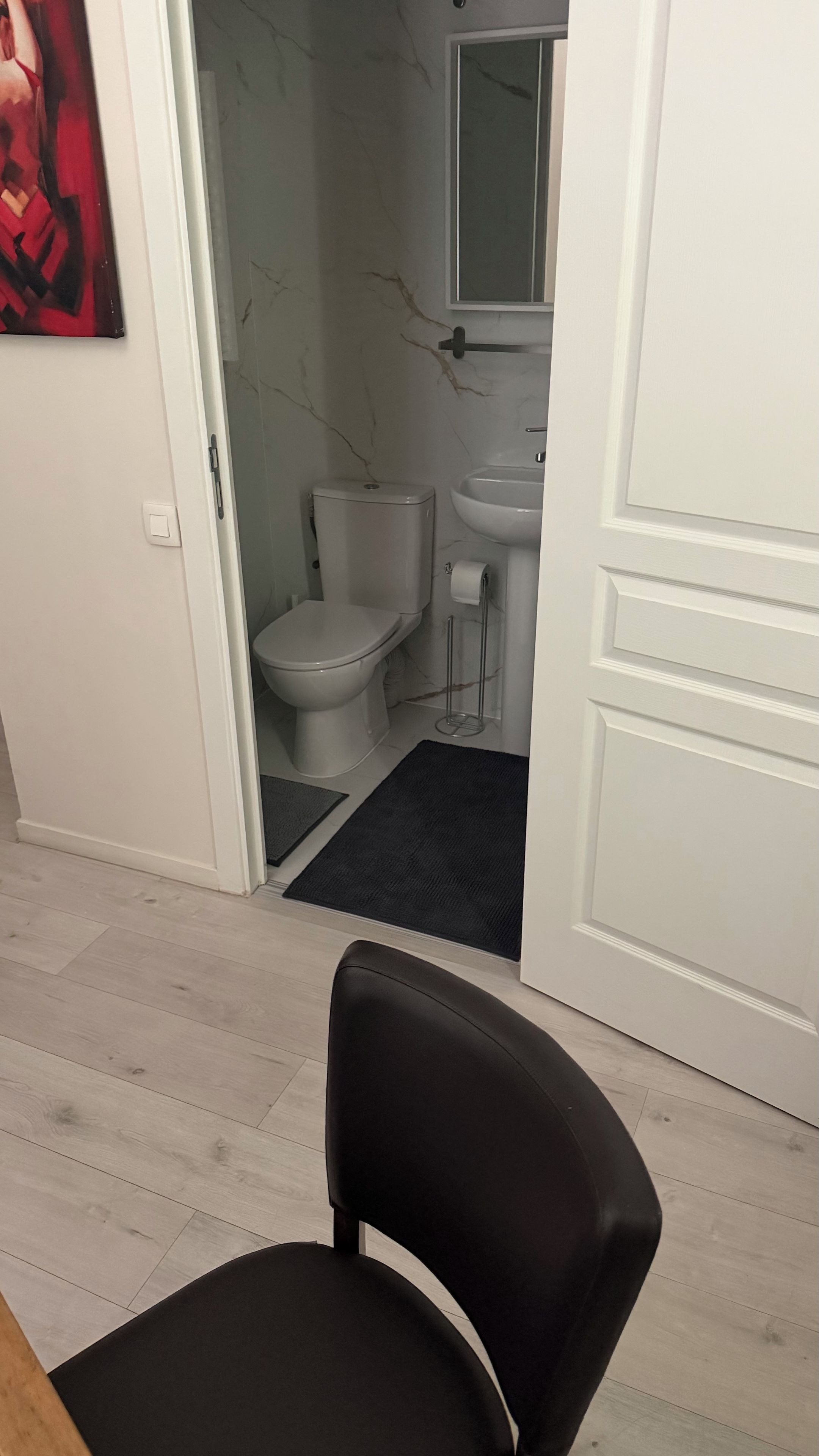 A bathroom with a toilet, sink, and marble walls.