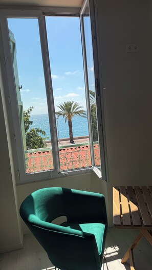 Ett rum med ett stort fönster, en grön stol och ett träbord.