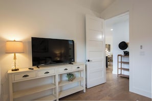 Ein modernes Wohnzimmer mit Fernseher, Lampe und einer weißen Unterhaltungsanlage mit Schubladen und Regalen.