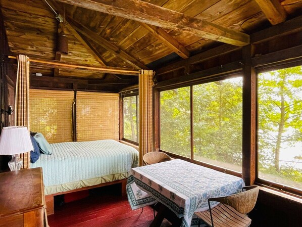 A cabin with two beds, a table, and a chair. - Lake Fairlee Waterfront Cottage with Screened Sleeping Porch & Beautiful Views (Fairlee)