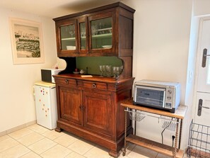 Een keuken met een houten kast, een witte koelkast en een magnetron op een tafeltje.