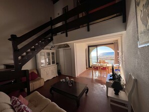 A living room with a staircase, a dining area with a view, and a balcony. - Duplex with panoramic view - 4 guests (Port Leucate)