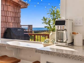 Eine Küche mit Kaffeemaschine, Grill und Meerblick.