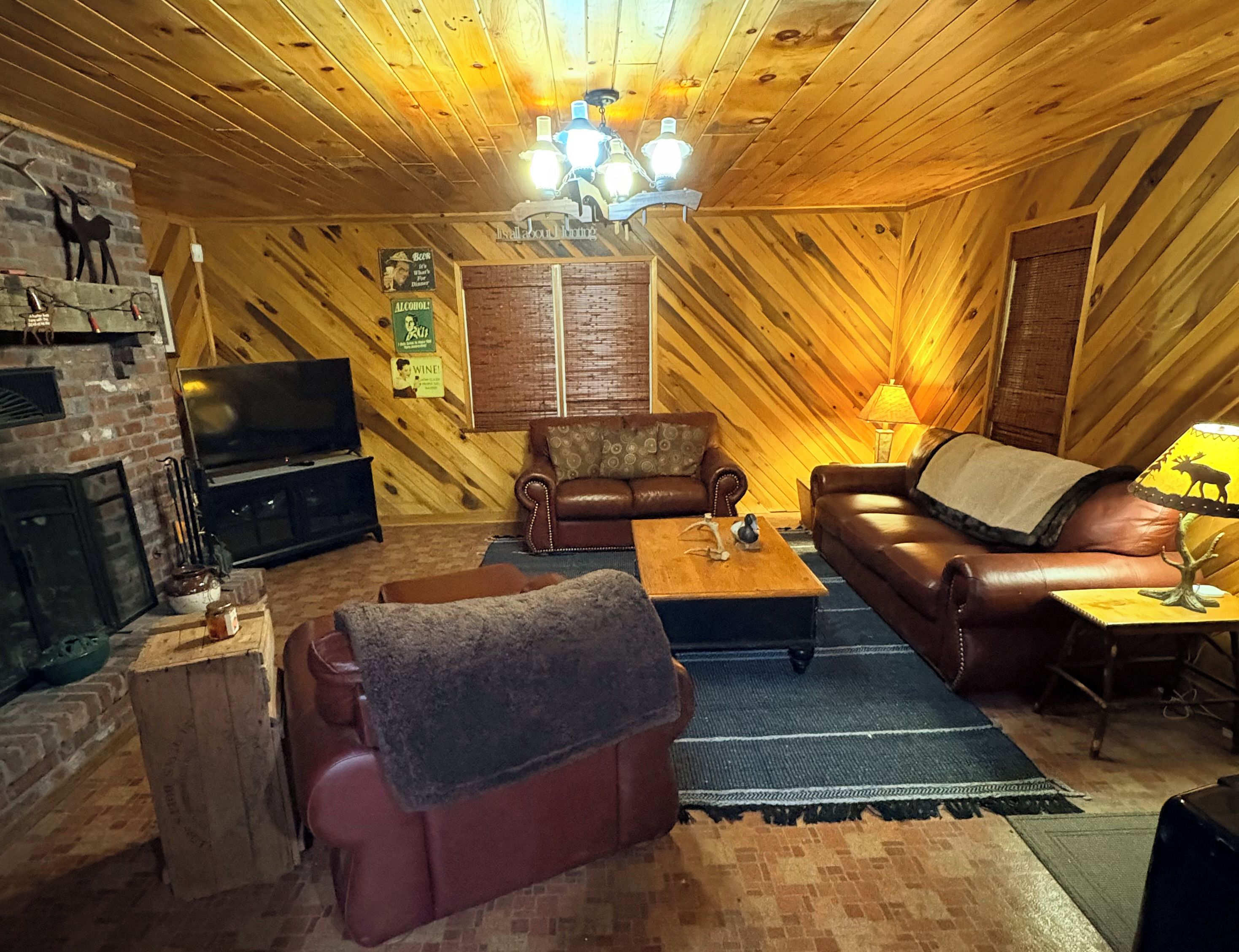 Una sala de estar acogedora con chimenea, sofás de cuero, una mesa de centro y un televisor.