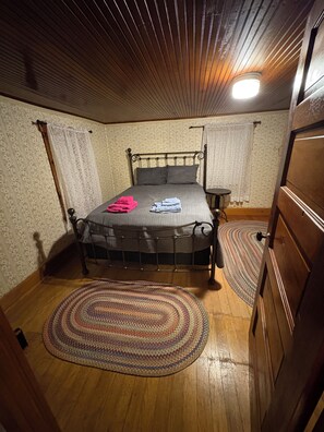 A bedroom with a bed, a bedside table, a lamp, and a patterned rug.