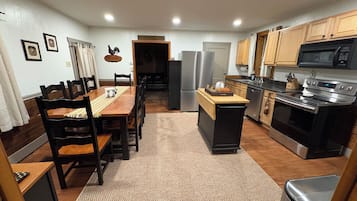 A compact kitchen with wooden cabinets, a stainless steel refrigerator, a microwave, and a stove.
