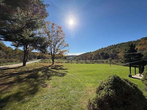A grassy field with a tree and a gazebo.