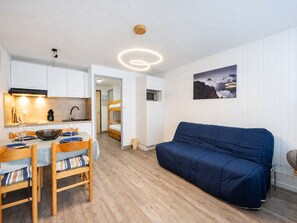 En kompakt bolig med tekøkken, spiseplads og sofa.