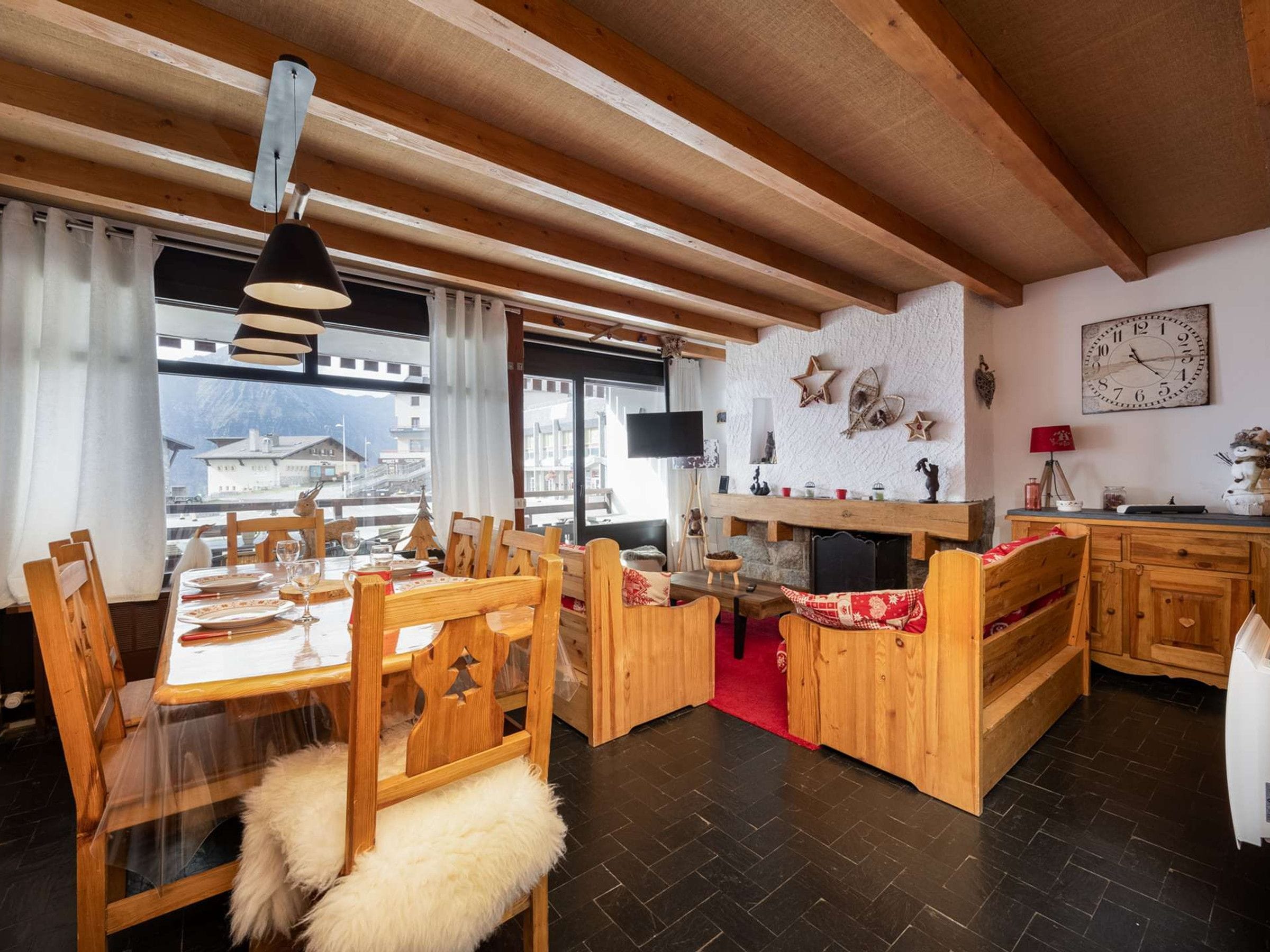 A cozy dining area with wooden furniture, a fireplace, and a view of the mountains.