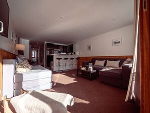 Ein geräumiger Wohnbereich mit einer Couch, einem Esstisch und einer Küche im Hintergrund.