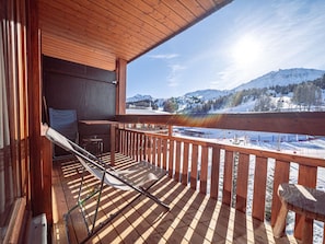 Ein Holzbalkon mit Blick auf eine verschneite Berglandschaft.