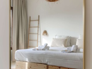 A neatly made bed with white linens and towels, a wooden ladder against the wall, and a simple wall-mounted light fixture. - Suspended villa, sea view - 10 guests (Le Lavandou)
