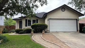 Une maison d’habitation avec un garage, une allée et une pelouse bien entretenue.