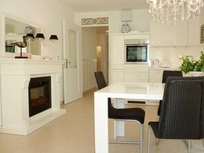 Eine moderne Küche mit weißem Kamin, einem Esstisch mit Stühlen und einer Pendelleuchte.