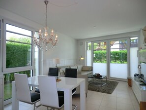 A modern living room with a dining area, large windows, and a chandelier. - 3 in Castle by the Sea (Wyk auf Foehr)