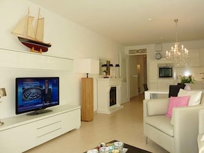 A modern living room with a flat-screen TV, a fireplace, a sofa, and a chandelier. - 3 in Castle by the Sea (Wyk auf Foehr)
