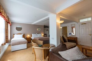Habitación de hotel con dos camas, un sofá, una mesita y un espejo.