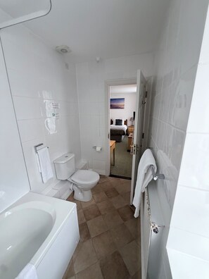 A bathroom with a bathtub, toilet, and a shower area. - Tyacks Hotel (Camborne)