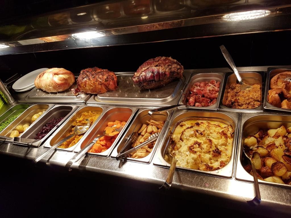 A buffet with various food items including meats, vegetables, and desserts.