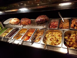 A buffet with various food items including meats, vegetables, and desserts.
