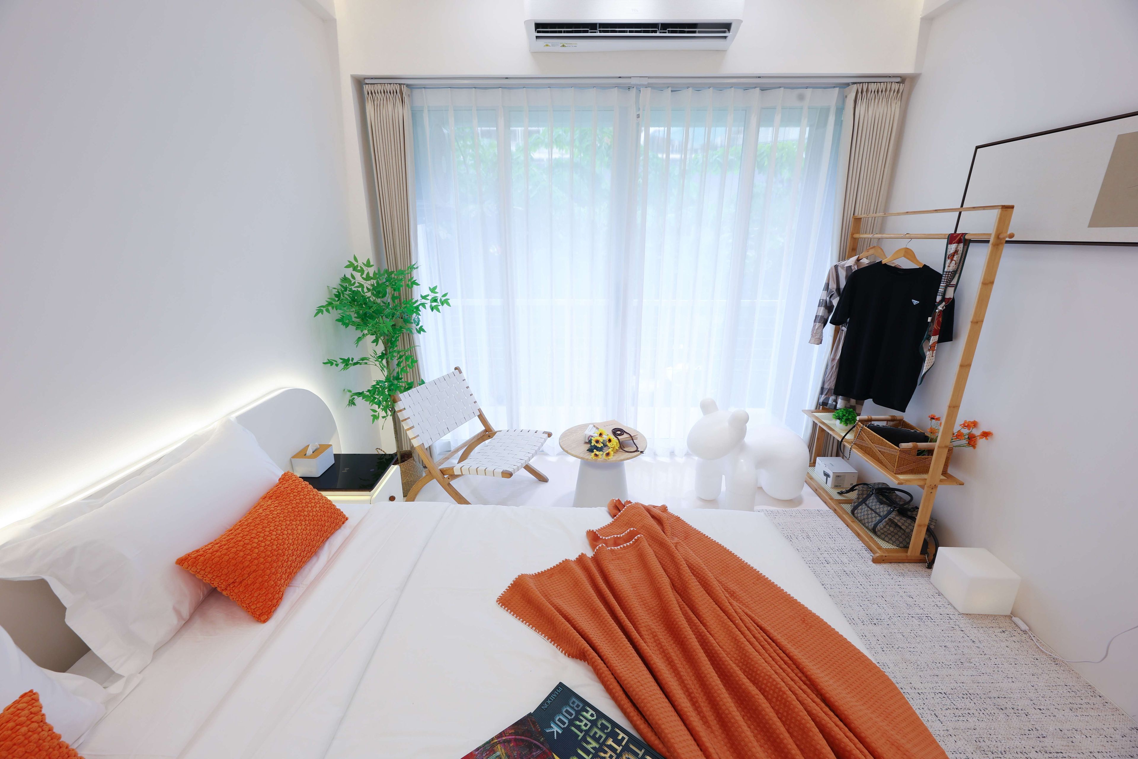 A hotel room with a bed, a chair, a small table, a wardrobe, and a window with curtains.