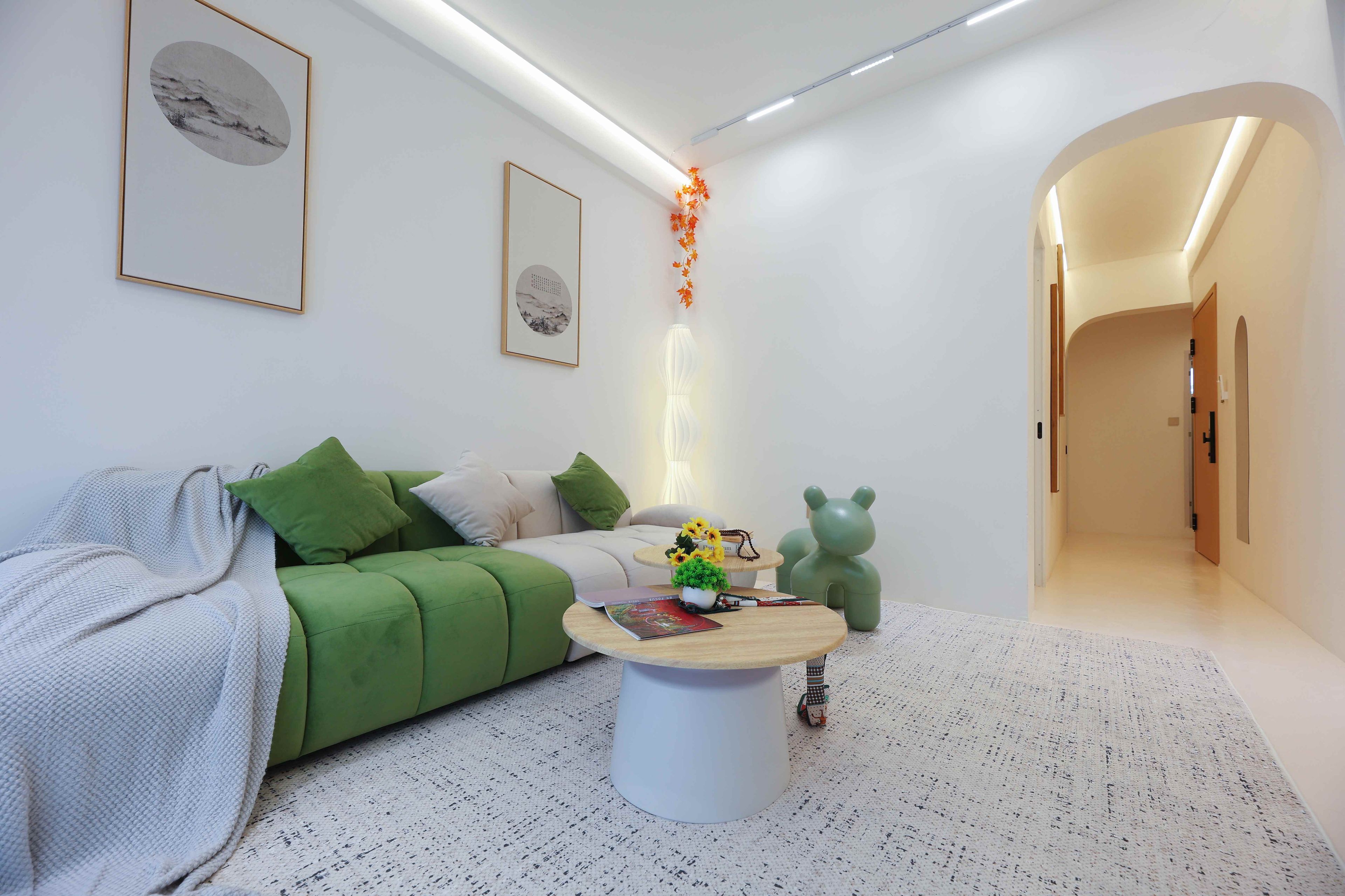 A modern living room with a green sofa, a coffee table, and a bear-shaped decoration.