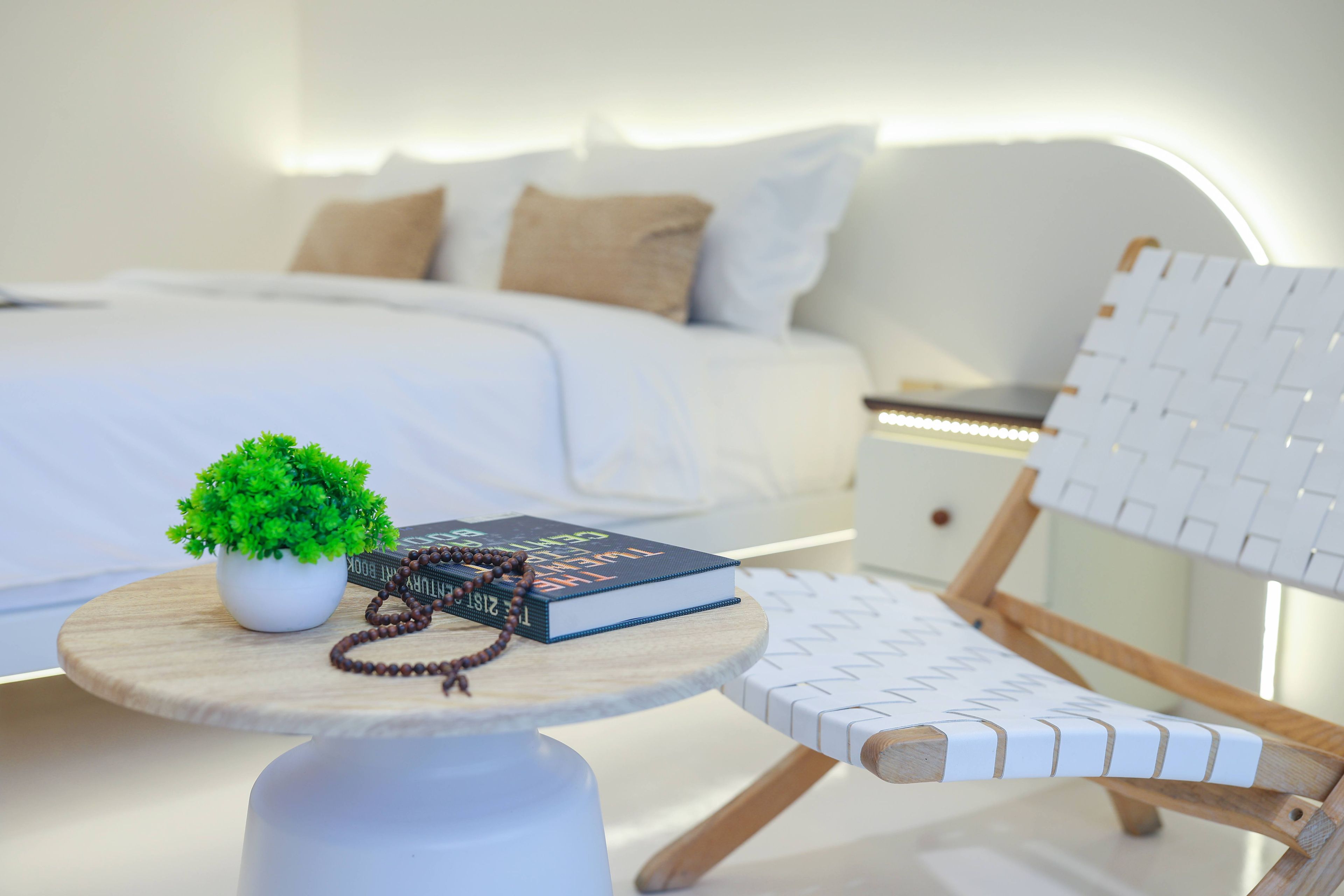 A neatly arranged bedroom with a bed, bedside table, and a small seating area with a chair and a table.