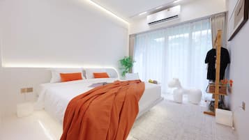A modern bedroom with a bed, bedside table, and a large window with curtains.