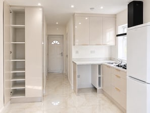 A modern kitchen with white cabinetry, a built-in oven, and a countertop with a sink.
