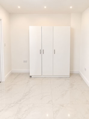A room with a large white wardrobe, a tiled floor, and recessed ceiling lights. - Manchester Hideout in Denton (Denton)