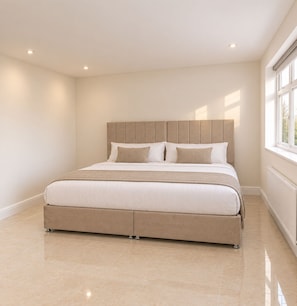 A bedroom with a large bed, a headboard, and a window.