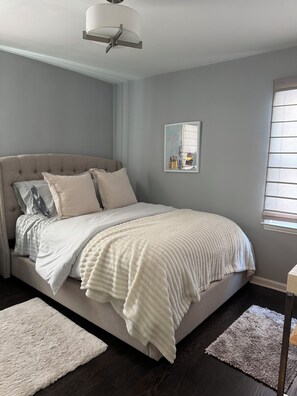 A bedroom with a large bed, a ceiling fan, a framed picture on the wall, and a window with blinds. - Stylish 2-Bedroom, 2-Bath Private Fenced Home in Royal Oak (Royal Oak)