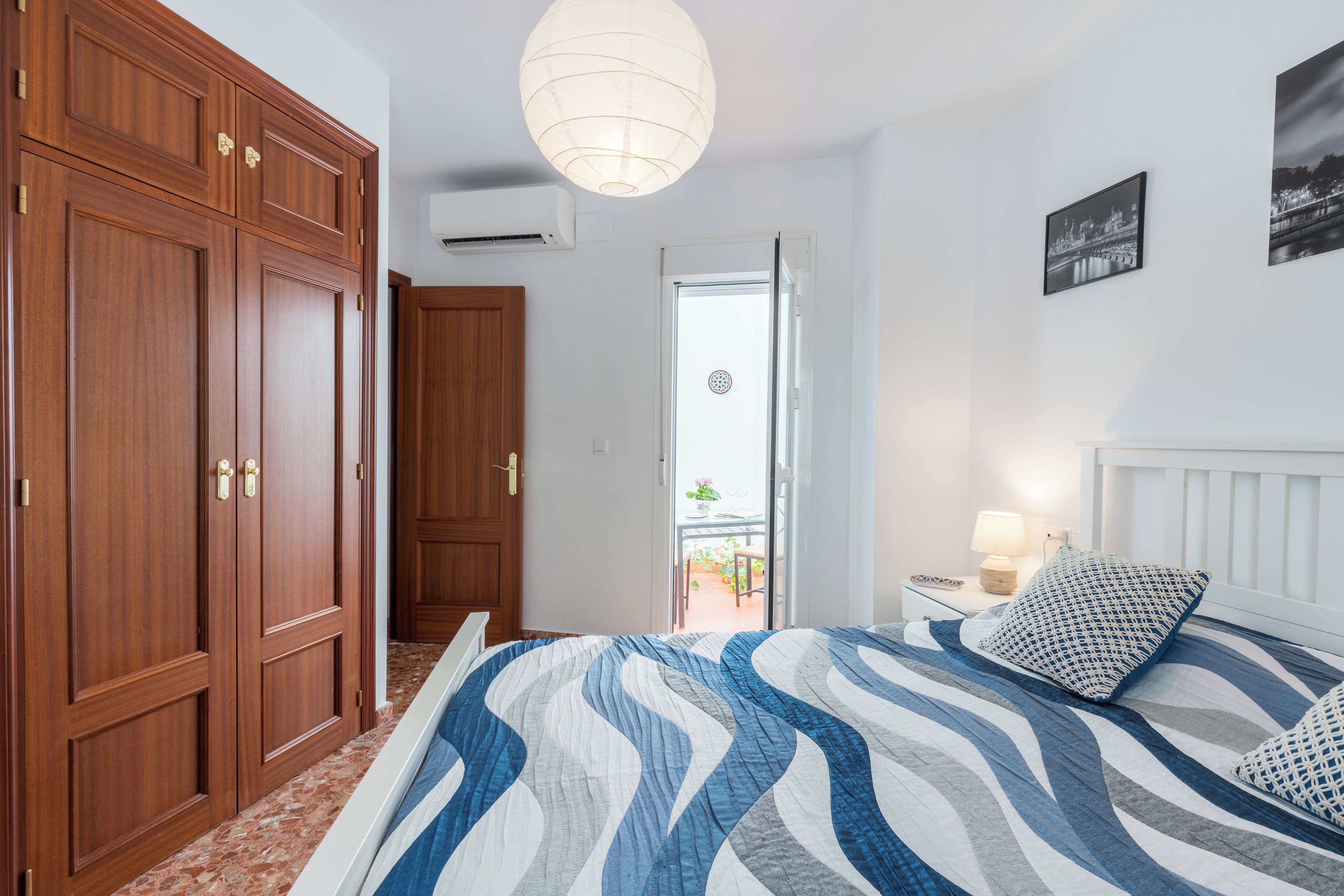 Ein Schlafzimmer mit Bett, Kleiderschrank, Nachttisch und Wandlampe.