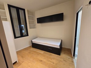 A small room with a bed, a window, and built-in shelving. - Vrbo Property (Marseille)