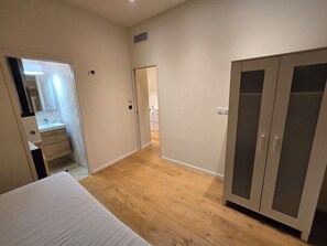A bedroom with a bed, a wardrobe, and a bathroom visible through an open door. - Vrbo Property (Marseille)