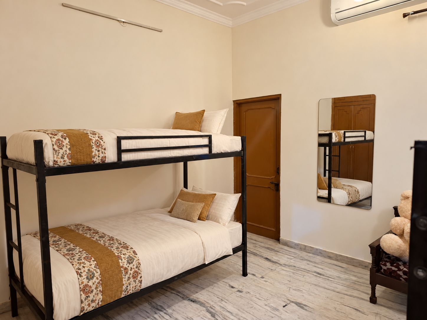 Uma cama beliche com estrutura de madeira e uma cama de baixo com coberta estampada.