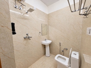 Een badkamer met een douche, wastafel, toilet en een spiegel.