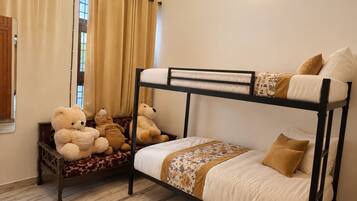 Une chambre avec un lit superposé, une fenêtre, des rideaux et un ours en peluche.