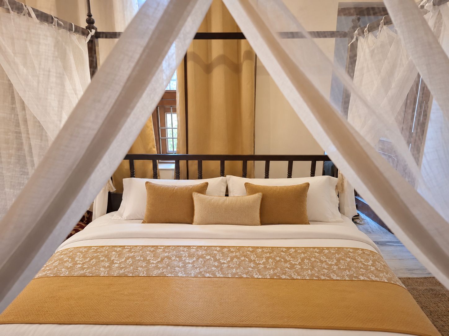 Un lit à baldaquin, avec une tête de lit en bois et une couvre-lit à motifs floraux.