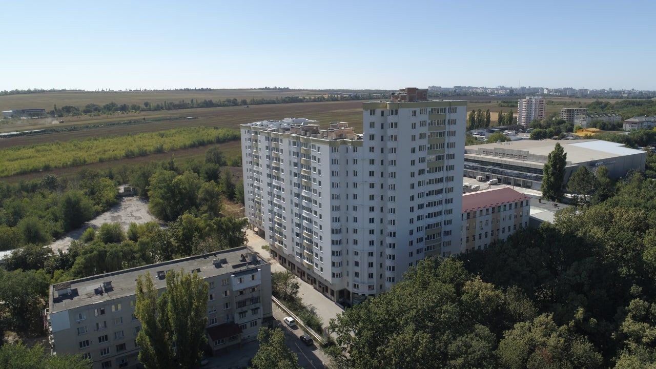 Un immeuble de grande hauteur, composé de plusieurs étages, entouré de verdure et d’autres bâtiments.