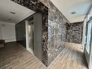A modern interior with a marble wall, a wooden floor, and a glass door. - Brilliant 1-bedroom apartment with AC in charming Chișinău near  Airport. (Chișinău)