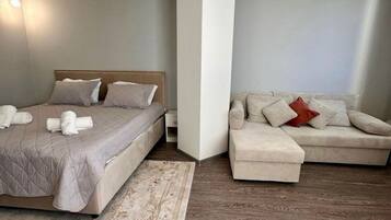 A modern bedroom with a bed, a sofa, and a patterned rug.