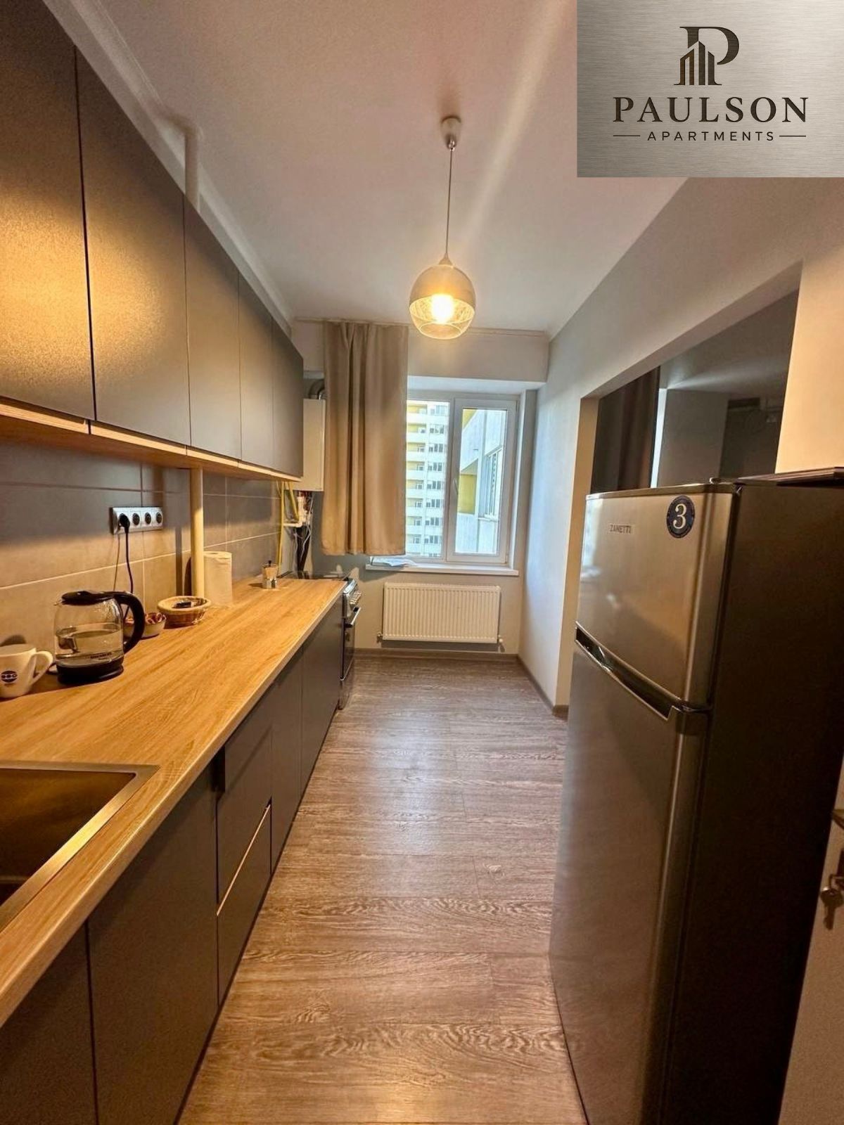 A modern kitchen with a wooden countertop, stainless steel appliances, and a window with a view.
