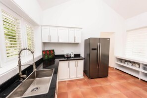 A kitchen with white cabinets, a stainless steel refrigerator, and a black countertop. - Private Villa with Pool, Chef, and Golf Cart, Punta Cana (Punta Cana)