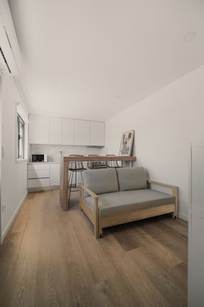 Een moderne keuken met witte kasten, een houten eettafel en een ingebouwde bank met kussens.