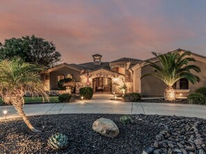 A residential property with a stone facade, a gated entrance, and landscaped gardens with palm trees and succulents. - AllStar Retreat! PickleBall/Soccer/Pool/Waterslide/Spa/Splash Pad/Putting Greens (Queen Creek)