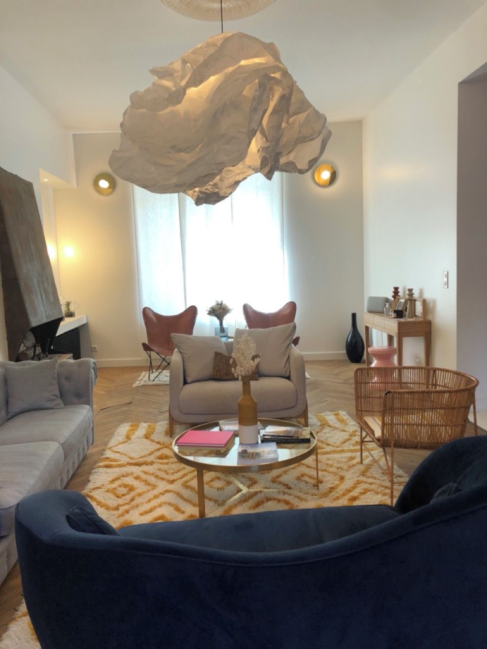 En moderne stue med en stor, abstrakt lampe, en sofa, et sofabord med dekorative genstande og en tæppe med et mønster.