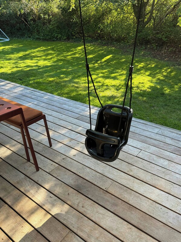 A wooden deck with a swing chair and a table.