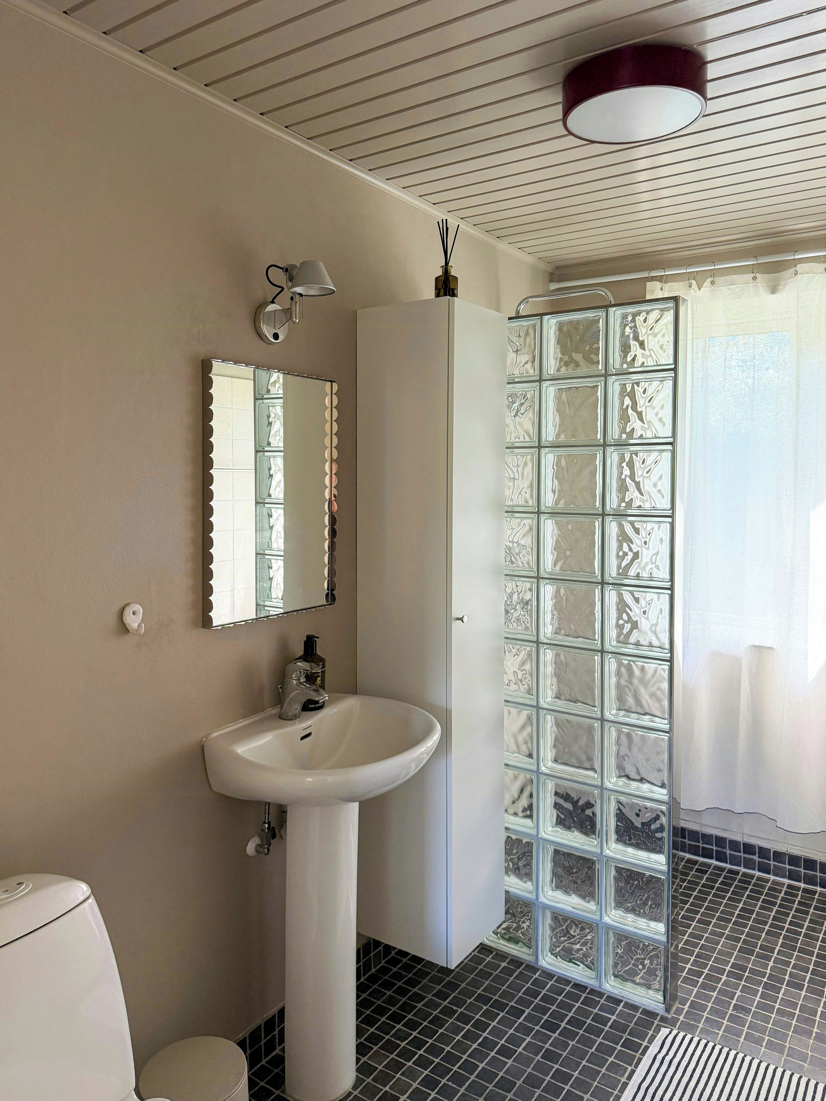 A bathroom with a white sink, a mirror, a toilet, and a shower with frosted glass doors.